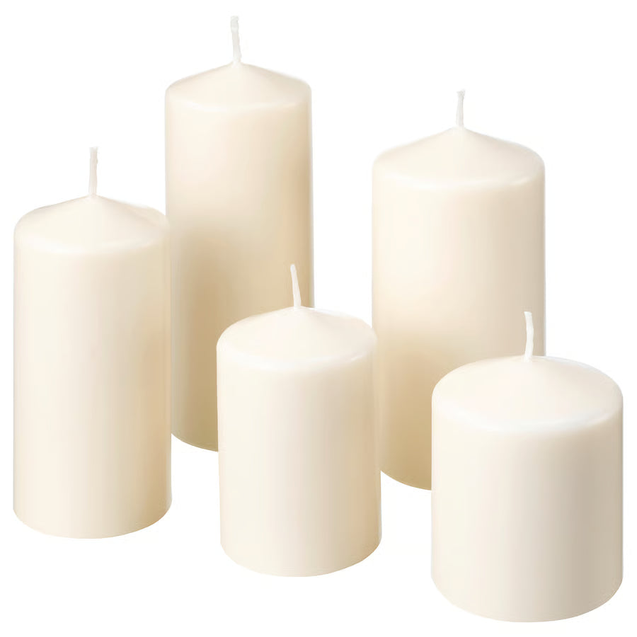 Set of five white candles of different sizes on a white background