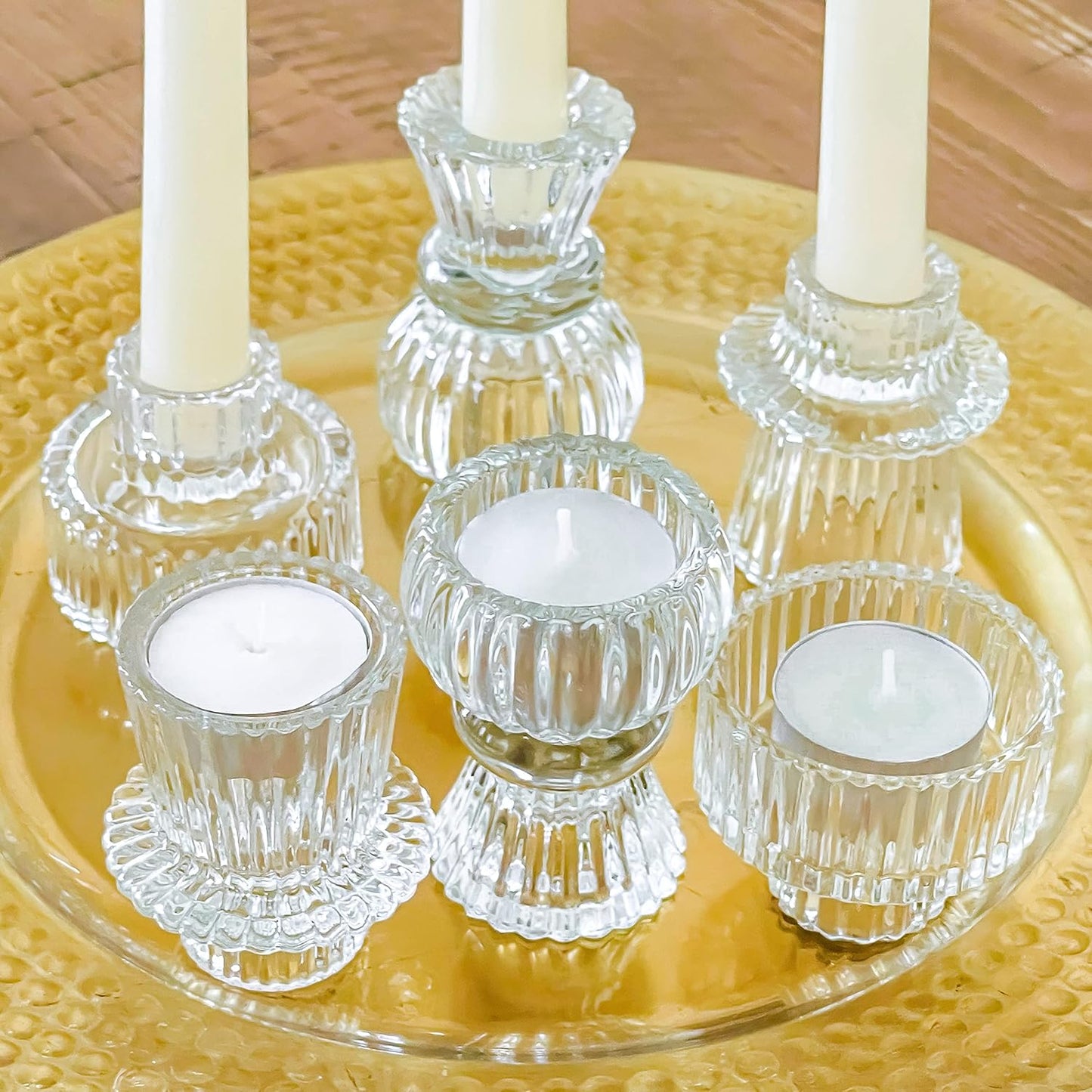 Clear glass candle holders with white candles on a yellow plate.