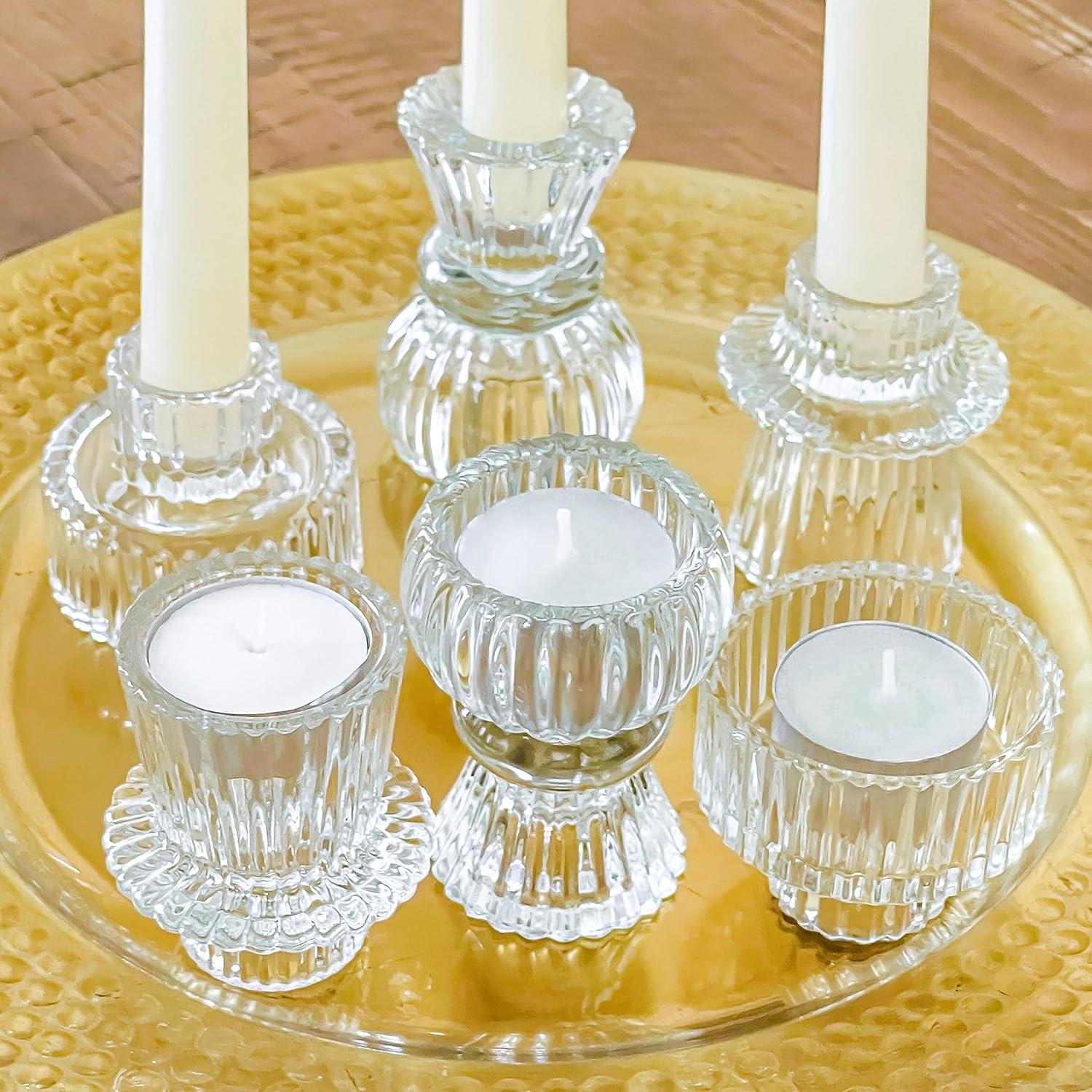 Clear glass candle holders with white candles on a yellow plate.