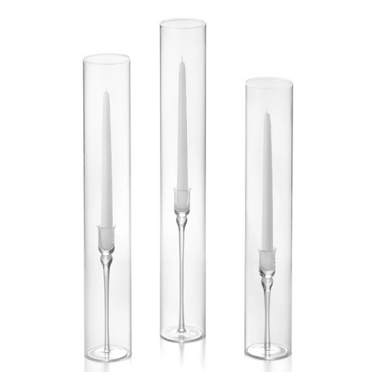 Three clear cylindrical candle holders with white candles on a white background